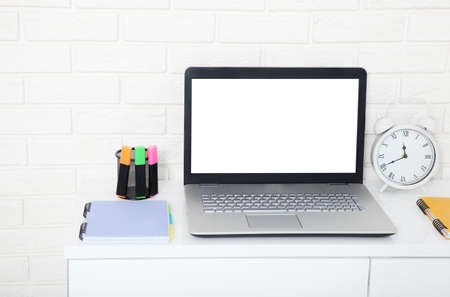 Education accessories on the table near brick wall. Empty computer and mobile screen with place for...