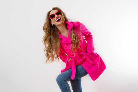 Close up happy girl in red sunglasses and pink coat isolated on white background. excited, shock and surprised young woman, trendy outfit. Fashion and shopping concept. long wavy hair. selective focusの写真素材