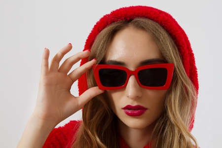 Closeup woman face in red sunglasses isolated on white background. Girl in red hoodie sweatshirt and...