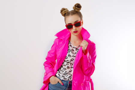 Happy, shock, excited woman face closeup. Girl in bright pink autumn clothes, red sunglasses isolated on white background, copy space. Beautiful female surprised, cheerful. Fun funny model screamingの写真素材