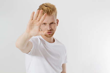 Stop hands sign. Young man in blank template white t shirt showing stop gesture. Redheaded and red beard guy isolated. hazard protection concept. Copy space and mock up on t-shirt. selective focusの写真素材