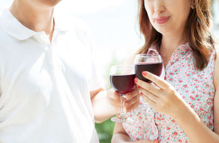 Middle-aged couple drinking wine on the summer terrace - cropped image.の写真素材