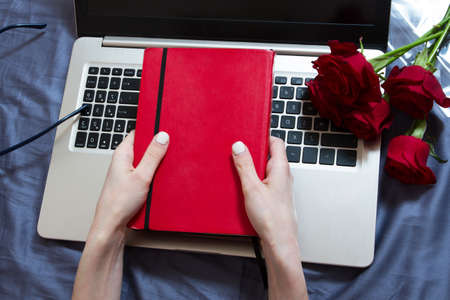 Hands, computer keyboard, bed top view. Workplace background, work at home, notepad and flowers