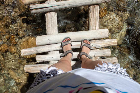 beautiful legs of a traveler on a wooden bridge by the river after a hike in the mountains. Travel...