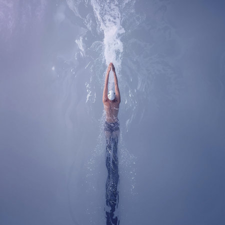Young woman swimming underwater in a pool with splashes of water.の素材