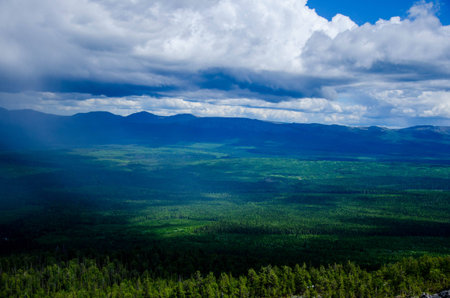 Green plain beneath the cloudy skies from the top of the mountainの写真素材