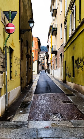 A small old pedestrian street in Italy, where the old pavement ends and asphalt beginsの写真素材