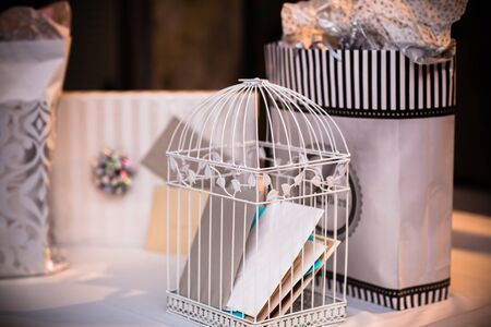 Close up of a bird cage with cards inside and gifts on the tableの写真素材