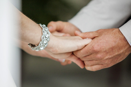Close up of couple holding hands on a wedding day