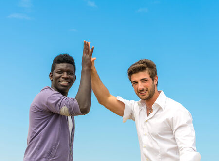 Caucasian man giving high five to a black man