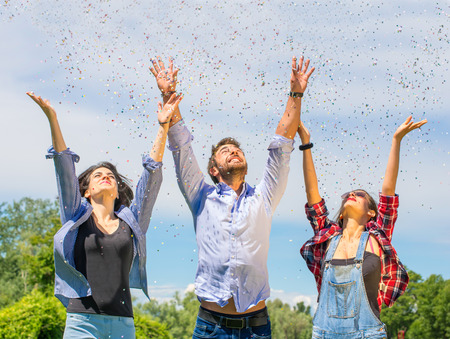 Group of friends throwing confetti in the air - happiness concept