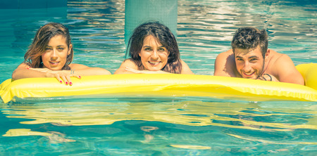 three friends on air bed in the swimming pool