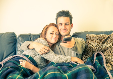 Happy couple watching television on the couch - family,recreation,leisure,togetherness conceptの写真素材