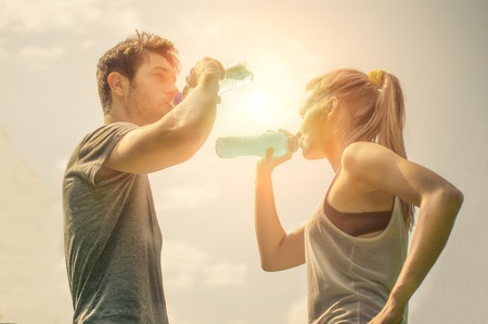 Couple drinking water after workout at sunsetの写真素材