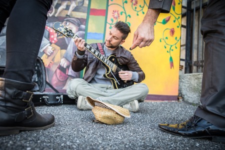 Street artist peforming om the streets - People listening man playing guitar and giving charityの写真素材