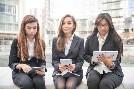 Business women of different ethnies working with tablets - Women sitting outdoors - Business,technology,multiracial conceptsの写真素材