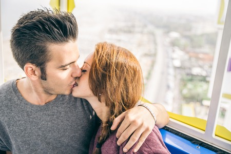 Couple enjoying a ride on a panoramic wheel - Lovers kissing and aerial view in backgroundの写真素材
