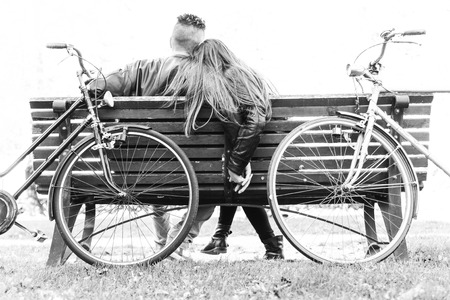 Couple on a bench - Two lovers sitting on a bench in a park and holding themselves by hands - Concepts of autumn,love,togetherness,relationshipの写真素材