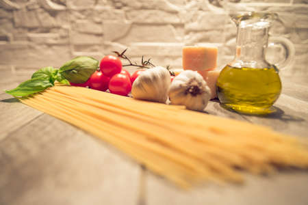 Pasta,tomatoes and spices on a wood table - Spaghetti and ingredients for a a great italian tomato sauceの写真素材