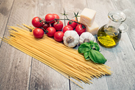 Pasta,tomatoes and spices on a wood table - Spaghetti and ingredients for a a great italian tomato sauceの写真素材