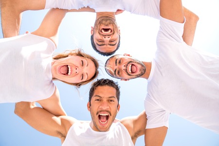 Group of friends on the beach smiling at camera - Four people of different ethnic having fun