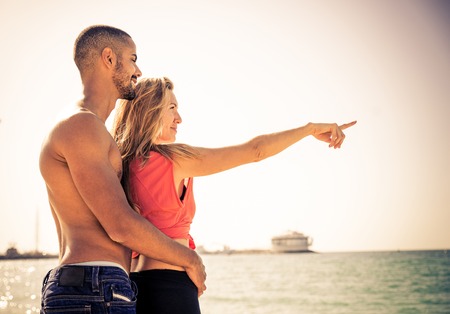 Couple of lovers watching the sunset - Man hugging his woman on the beachの写真素材