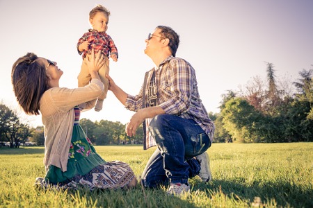 Happy family portrait - Portrait of young beautiful couple with kid having fun in a park - Vintage lookの写真素材