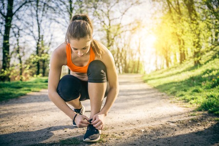 Young sportive woman getting ready to start running workout - Athlete running outdoors at sunset -...