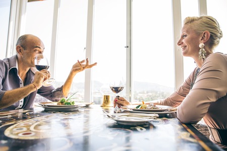 Beautiful happy couple having romantic dinner at sunset in a luxury restaurant - Woman and her husband celebrating wedding anniversaryの写真素材