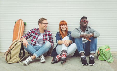 three mixed race friends sitting and having fun. concept about people and youthの写真素材