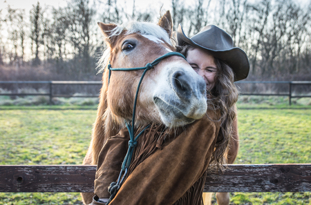 Funny portrait of a girl with an horse. Playing together at the farm. concept about people and animalsの写真素材