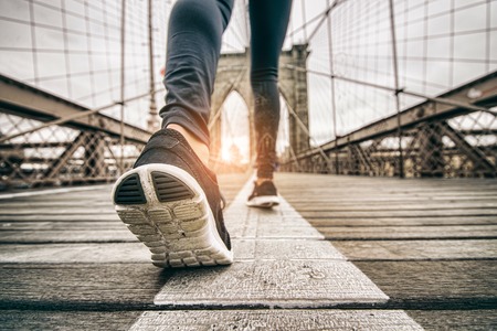 Woman running outdoors - Young sportive girl jogging at sunset on Brooklyn Bridge, close up on shoes