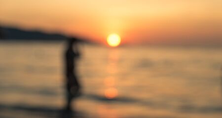 Blurred image of the sunset on the beach. silhouette of a peson enjoying the sunsetの写真素材