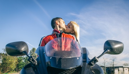 Happy young couple kissing on the motorcycle. Concept about love and transportationの写真素材