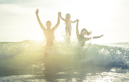 Happy family silhouette in the water. Jumping between the wavesの写真素材
