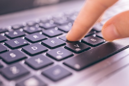 Close up on fingers texting on a computer keyboard