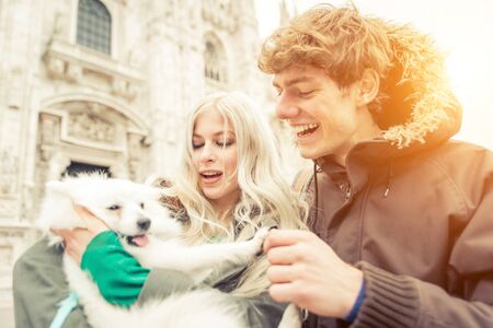 Young couple with dog walking in Milan city center. Duomo cathedral in the background. People and...