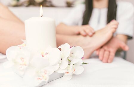 Close up of woman's feet and beauty saloon decorations. Beautician making foot massage. Concept about body care, spa and massagesの写真素材