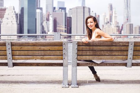 Mixed race woman sitting on a bench and looking at camera - Tourist visiting New Yorkの写真素材