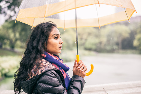 Woman walking in a park with umbrella while raining - Pretty girl waiting somebody under the rainの写真素材