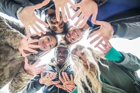 Multi-ethnic group of friends hanging out - Cheerful people meeting outdoors and having fun - People holding hands in circle formationの写真素材