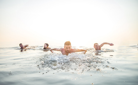 Group of friends swimming in the sea - Cheerful people having fun and enjoying summer vacationの写真素材