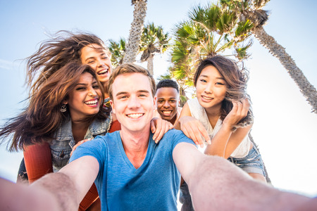 Multi-ethnic group of friends taking a self portrait picture with a camera phone - Cheerful people...