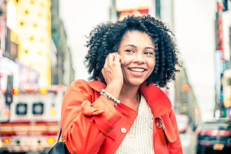 Afroamerican woman speaking at phone, urban blurred background - Portrait of pretty girl talking at somebody on cellphone and smilingの写真素材