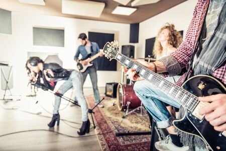 Rock band recording a music track in a studio - Friends performing music in a recording studioの写真素材