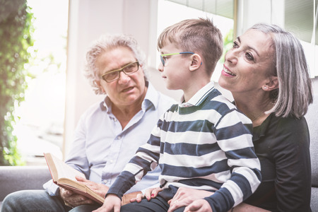 Grandparents spending time with grandson. reading him story in the living roomの写真素材
