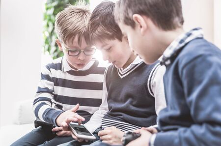 Three children using smart phone and learning about techologyの写真素材