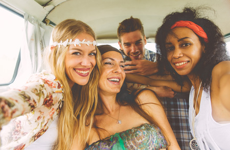 Hippie friends having fun into a vintage van, taking nice picturesの写真素材