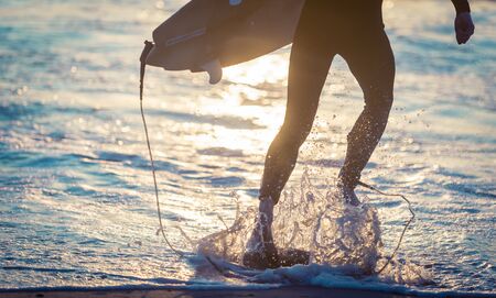 Surfer running in the water with the boardの写真素材