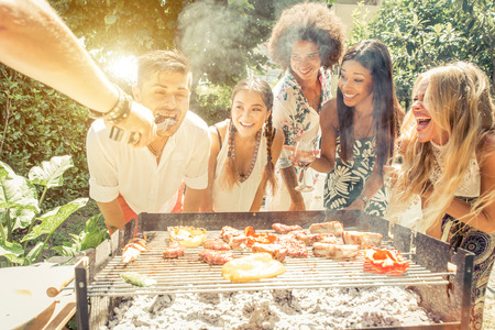 Group of mixed race friends making barbecue in the backyard and celebrate with good moodの写真素材